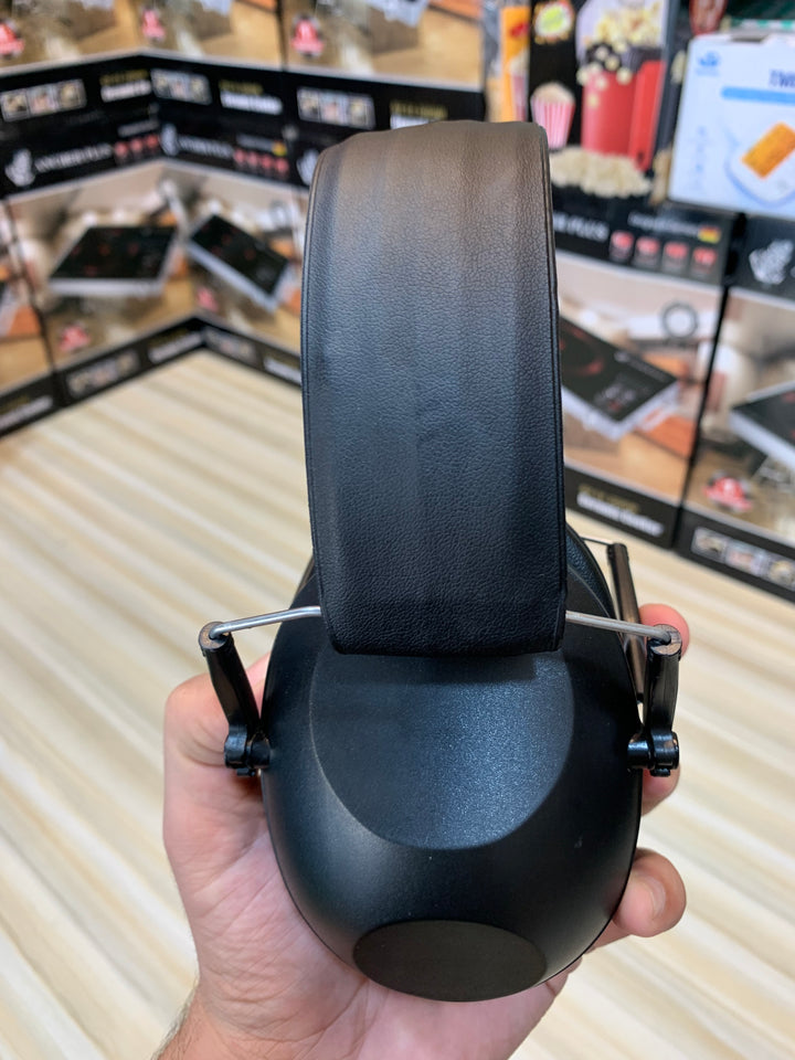 Man wearing noise-cancelling ear muffs at a shooting range in Pakistan for ear protection during practice.